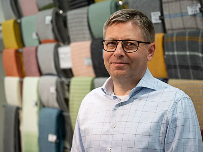 Petter Magnusson framför vägg av filtar i olika färger